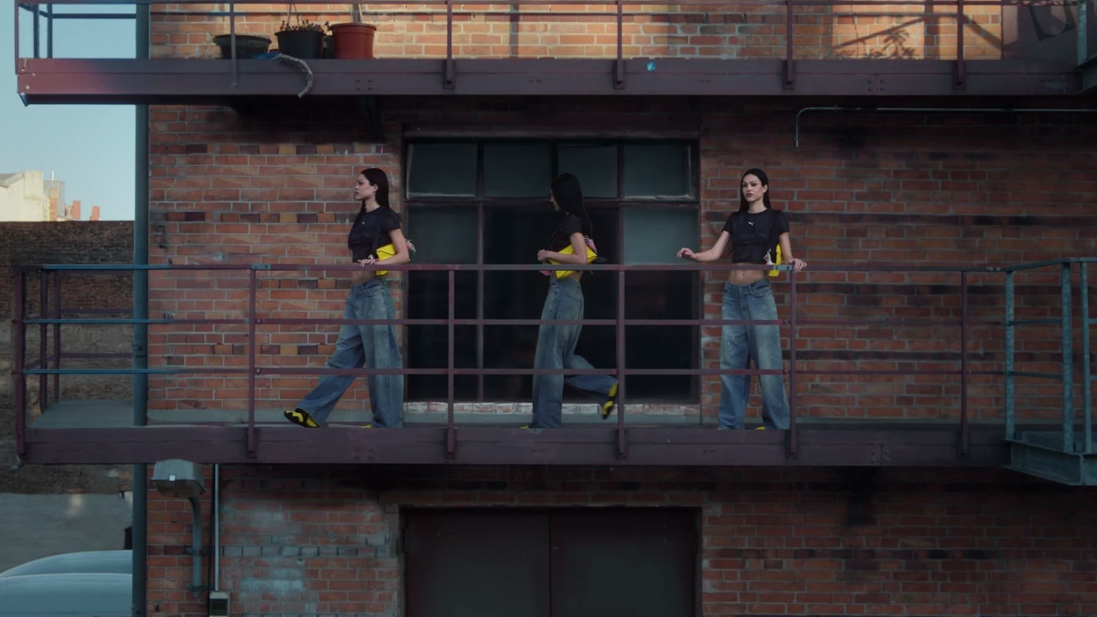 Custom music for commercials: a model in yellow Puma sneakers walking along the balcony of a brick building, from a Puma campaign video