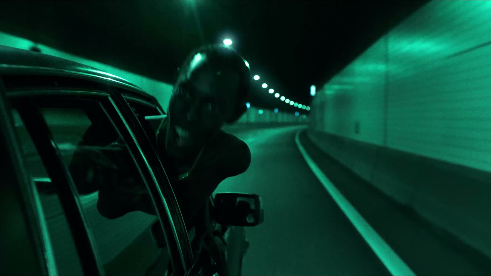 Sonic branding for fashion brands: a masked figure leans out of a car window in a green-lit tunnel in the Banlieue fashion film