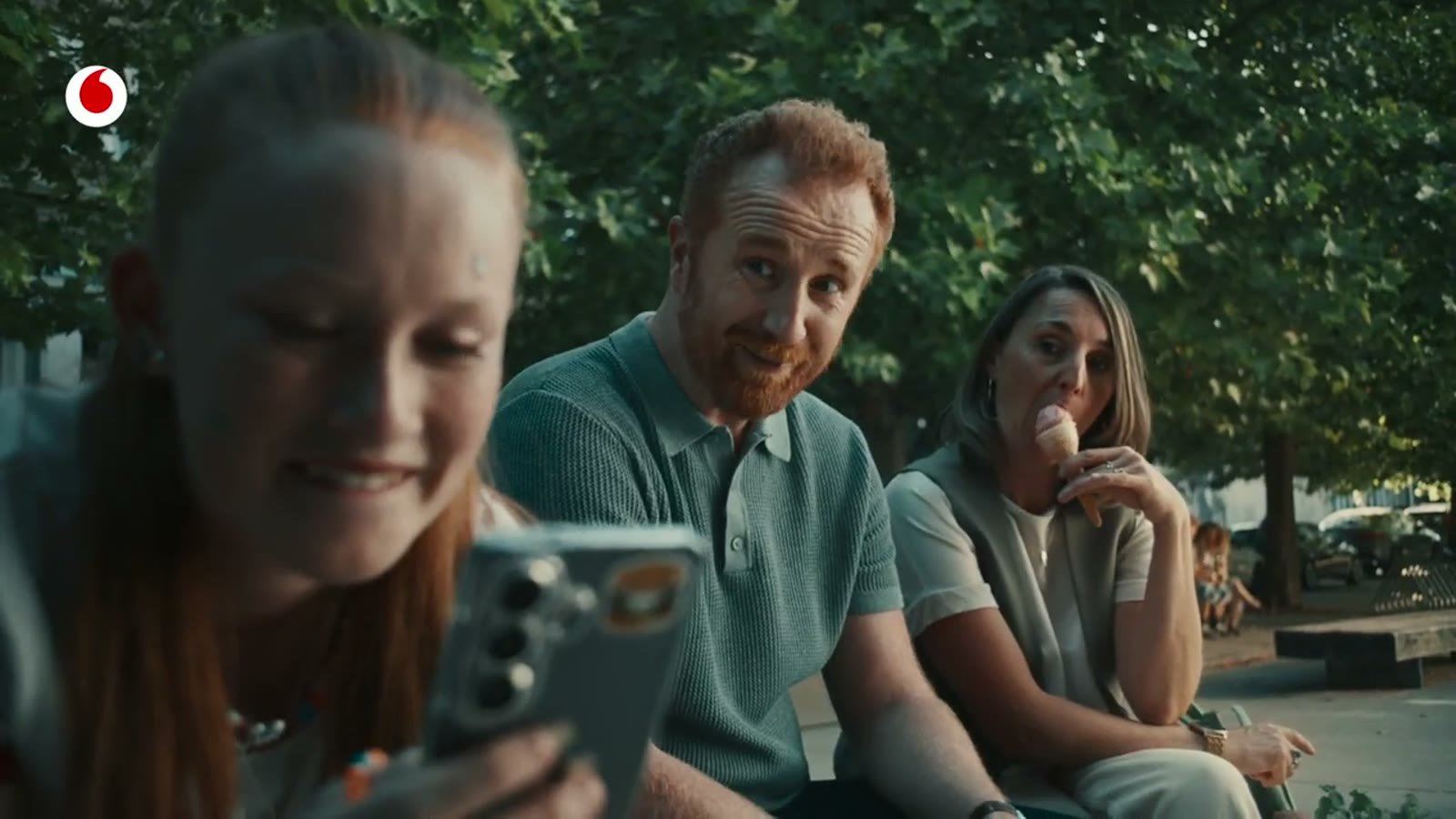 Sonic branding for telecom companies: a family on a bench looks at a phone in a Vodafone Germany TV commercial